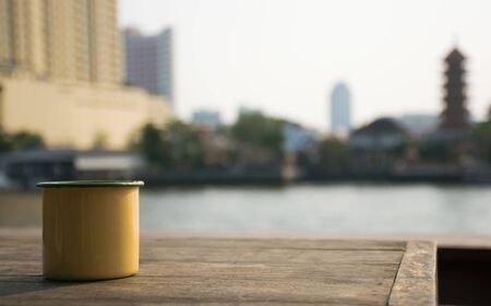 Close up Yellow cup on a wooden table next to the river.の写真素材