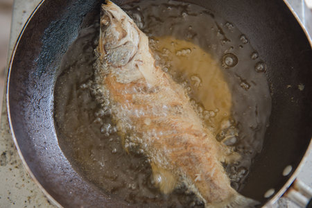 Fish fried in boiling oil on pan steel . closeupの写真素材