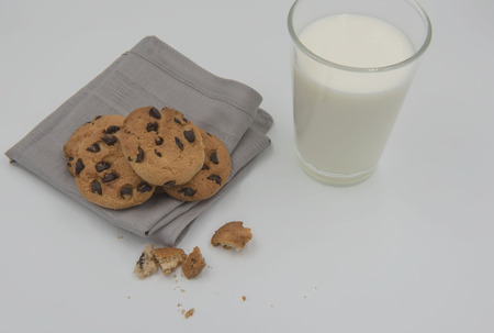 Chocolate chip cookie on a cloth and glass of milk on white background.の写真素材