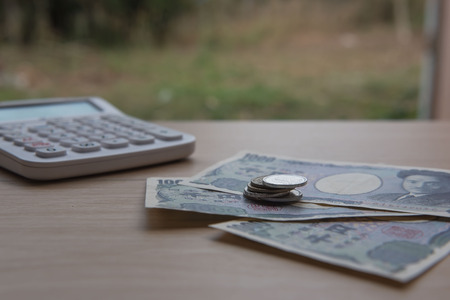 Closeup coin yen and banknotes Japanese and Calculator on wooden background. Currency of Japan.の写真素材