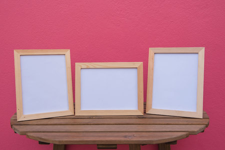 Three photo Frame on a wooden on pink background .