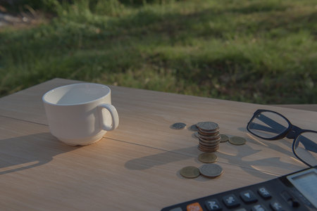 Business on financial report . Closeup coin and banknotes and Calculator , cup on wooden table.の写真素材