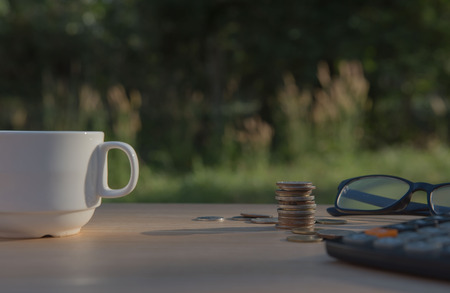 Business on financial report . Closeup coin and banknotes and Calculator , cup on wooden table.の写真素材