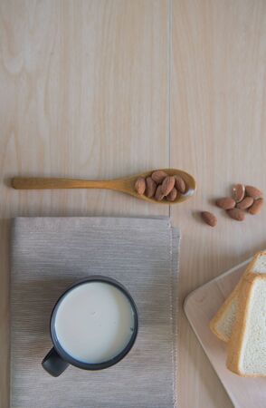 Top view cup of milk with bread and  Almonds for breakfast  on wooden table.の写真素材