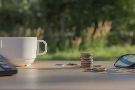 Business on financial report . Closeup coin and banknotes and Calculator , cup on wooden table.の写真素材