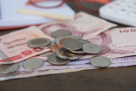 Business on financial report . Closeup coin and banknotes and Calculator , book on wooden background.の写真素材