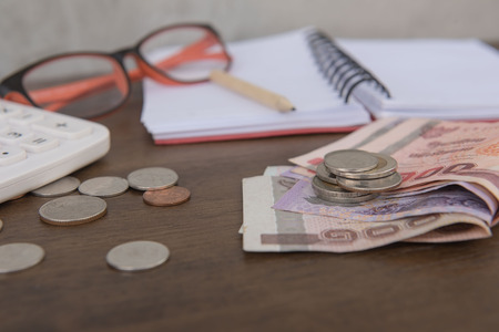 Business on financial report . Closeup coin and banknotes and Calculator , book on wooden...