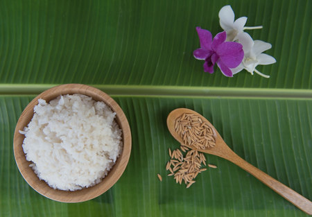 Top view Cooked rice in bowl on green banana leaf and paddy in spoon and orchid .の写真素材