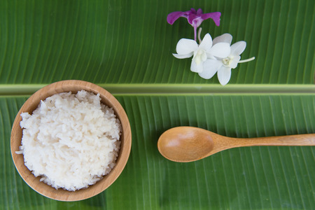 Top view Cooked rice in bowl on green banana leaf spoon and orchid .の写真素材