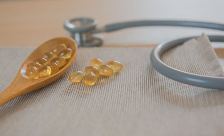 oil gel capsules and stethoscope . Natural Supplement for vascular health on wooden background.の写真素材