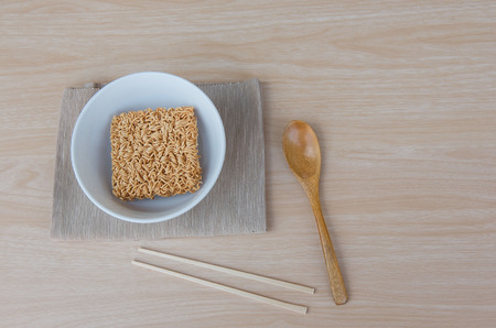 Top view Instant noodles in white dish spoon and chopsticks on wood background.の写真素材