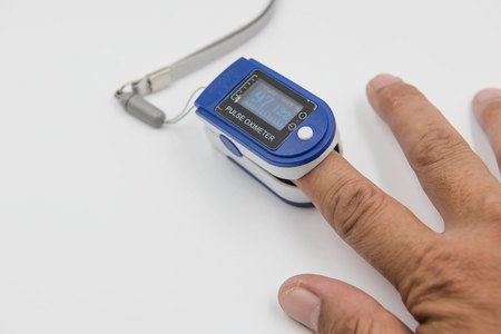 Pulse oximeter in a male patient's fingertip  on white background.