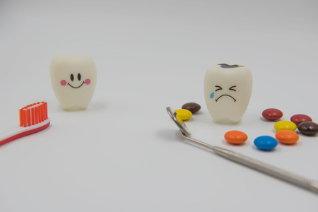 Model Cute toys teeth and colorful candy in dentistry on a white background.