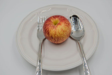 Red apple on plate and spoon ,fork  on white background , health concept .の写真素材