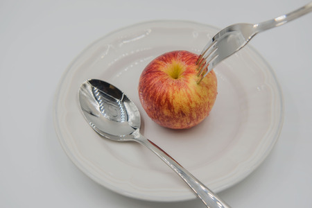Red apple on plate and spoon ,fork  on white background , health concept .の写真素材
