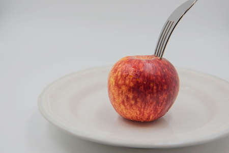 Red apple on plate and fork  on white background , health concept .の写真素材