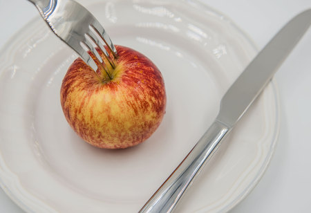 Red apple on plate and fork , knife  on white background , health concept .