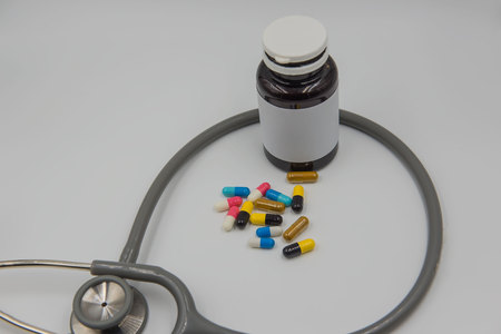 Capsules drug tablets and bottles and stethoscope on white background .の写真素材