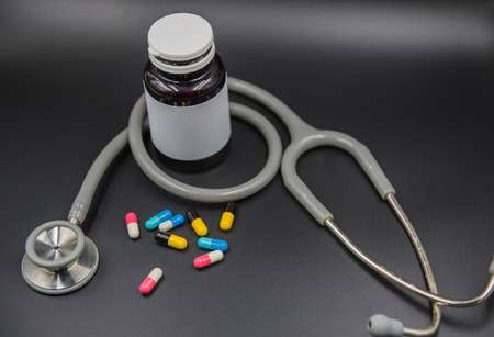 Capsules drug tablets and bottles and stethoscope on black background .の写真素材