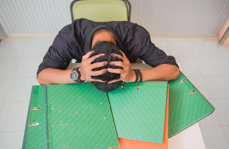 Businessmen to put his hand to the head , stressed because they have to work hard at office desk.の写真素材