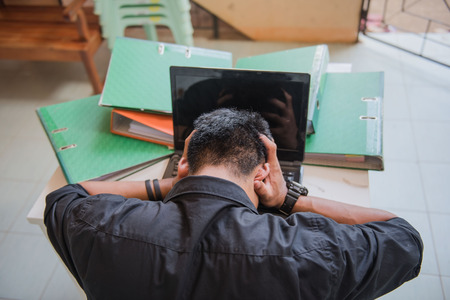 Businessmen to put his hand to the head and desktop computer , stressed because they have to work hard at office desk.の写真素材