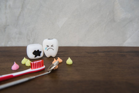 Model Cute toys teeth and colorful candy in dentistry on a wooden table and wall gray background.の写真素材