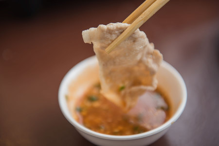 Hand holding pork using chopsticks and sauce shabu .の写真素材