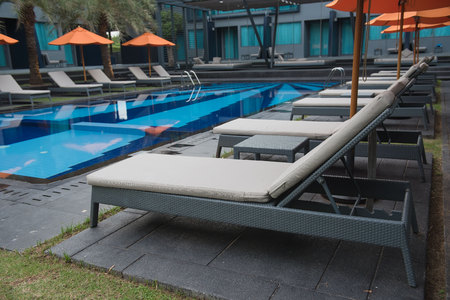 Sunbeds by the blue swimming pool .