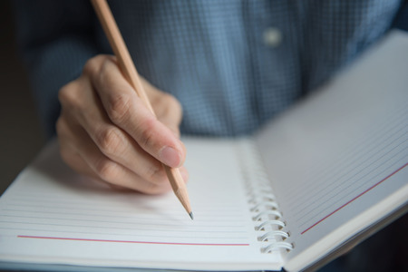 Closeup hand Woman writing notebook with pencil .