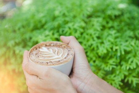 Women holding a hot cup of coffee in hands in coffee shop .の写真素材
