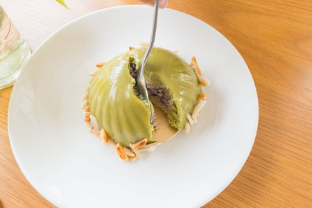 Green dessert  is made from green tea with red bean paste. In a white plate on the table .の写真素材