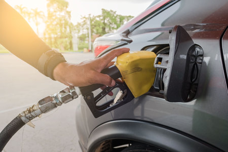 fill up with petrol in gas station by person .