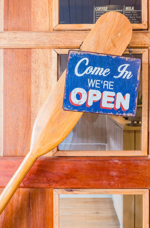 âCome in weâre open â metal label Hang on a wooden door at a restaurant . vintage tone .の写真素材