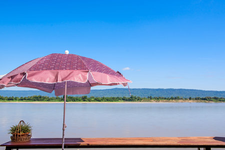 At river view in quiet summer blue sky, wind, sunshine and colorful umbrella .の写真素材