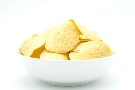 Fried yellow potato chips in a bowl  isolated on white background .