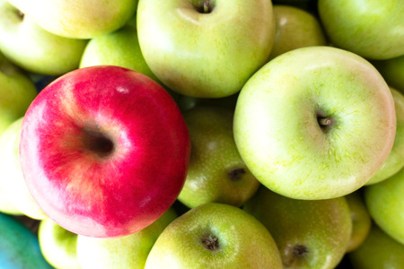 one  red apple among group of many green apples .