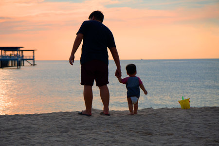 Family concept Silhouette rear view of man and on the beach near the sea and sky Twilight background for amazing landscape Happy freedom .の写真素材