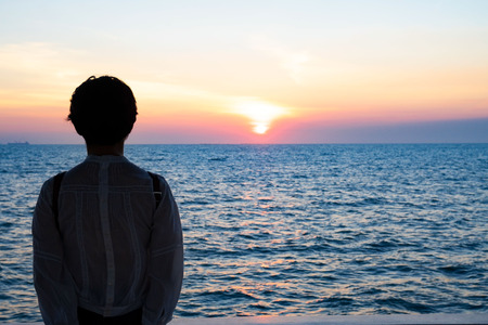 Silhouette rear view of young woman standing near the sea and sky Twilight background for amazing landscape Happy freedom for success and bliss concept.の写真素材