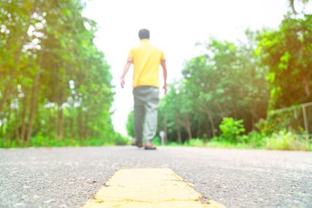 at countryside road and young man walking alone on the road .の写真素材