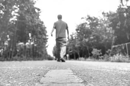 black and white at countryside road and young man walking alone on the road .