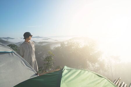 young woman standing for amazing landscape of blue sky and mountains in morning fog. Happy freedom for success and bliss concept.の写真素材