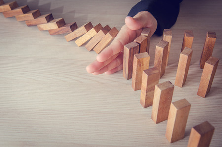Businesswoman hand stopping the domino wooden effect concept for business. Risk.