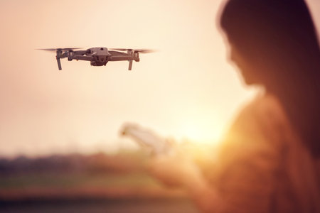 Closeup drone and blurred Woman operating a drone with remote control in sunset.の写真素材