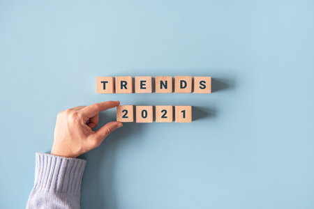 Hand holding wooden blocks with the word Trends 2021. Trend of changing something. Popular and...