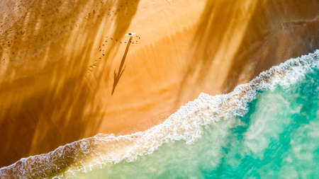 Freedom and happiness woman on beach. She is enjoying serene sea nature during travel holidays vacation outdoors sunset. Top view.の写真素材