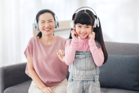 Happy daughter and mother listening music with headphones and earphones.の写真素材