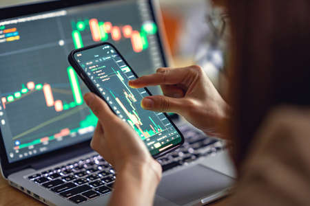 Closeup - Woman is checking Bitcoin price chart on digital exchange on smartphone, cryptocurrency...