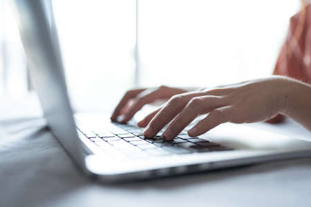 Closeup hand of a woman working and touching on laptop touchpad on wooden table at home.の写真素材