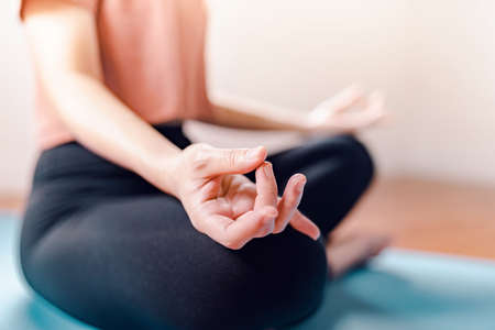 Close up - Woman practicing yoga lesson, breathing, relaxing, working out indoor at home. Well being, wellness concept.の写真素材