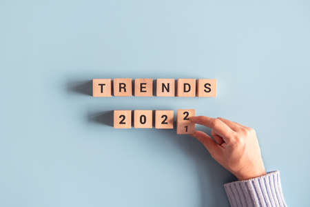 Hand of woman flips wooden blocks and change the 'TRENDS 2021' to 'TRENDS 2022'. New trends of fashion.の写真素材